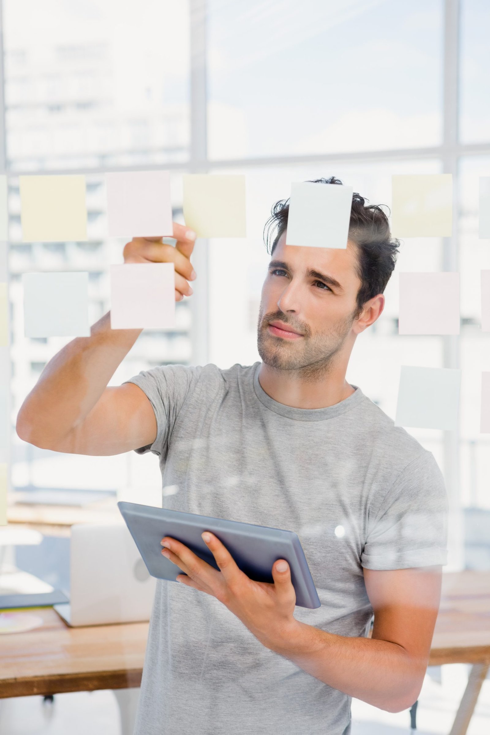 man holding digital tablet looking sticky notes scaled